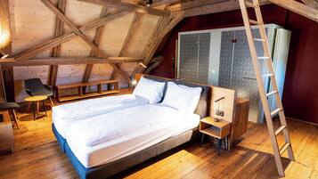 Un dormitorio con techo de madera, una cama, un escritorio, una silla y una escalera.