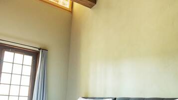 Quarto com cama, janela e vigas de madeira no teto.