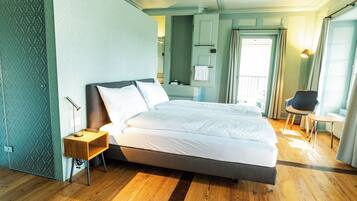 Una habitación de hotel moderna con una cama grande, una mesita de noche, una silla y un vestidor.