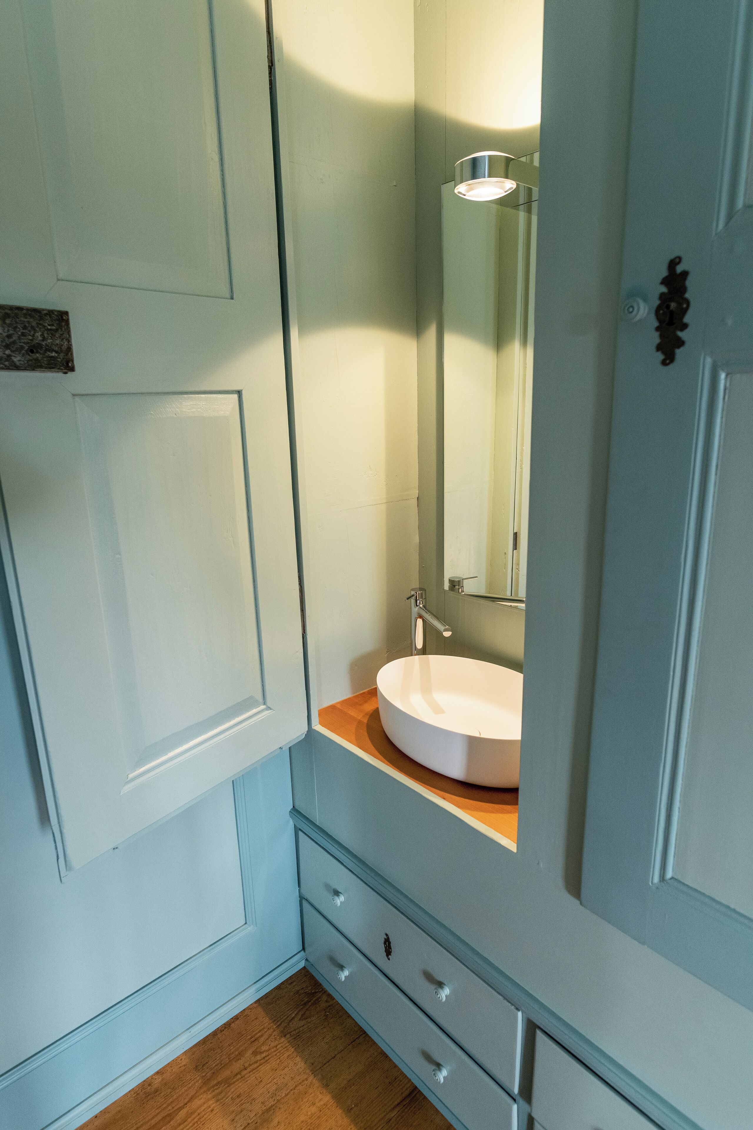 A bathroom with a white sink, a mirror, and a wooden countertop.
