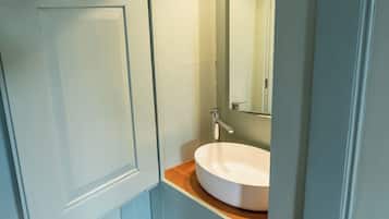 A bathroom with a white sink, a mirror, and a wooden countertop.