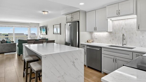 A modern kitchen with a marble island, stainless steel appliances, and light grey cabinetry. - Gulfstream Condos Unit 504 | Pool, Hot Tub & BBQ Areas | Private Balcony (Corpus Christi)