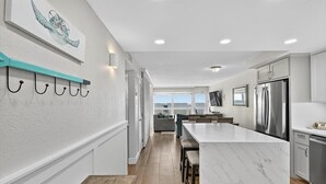 A modern kitchen with a marble island, stainless steel appliances, and a teal-colored wall-mounted rack. - Gulfstream Condos Unit 504 | Pool, Hot Tub & BBQ Areas | Private Balcony (Corpus Christi)