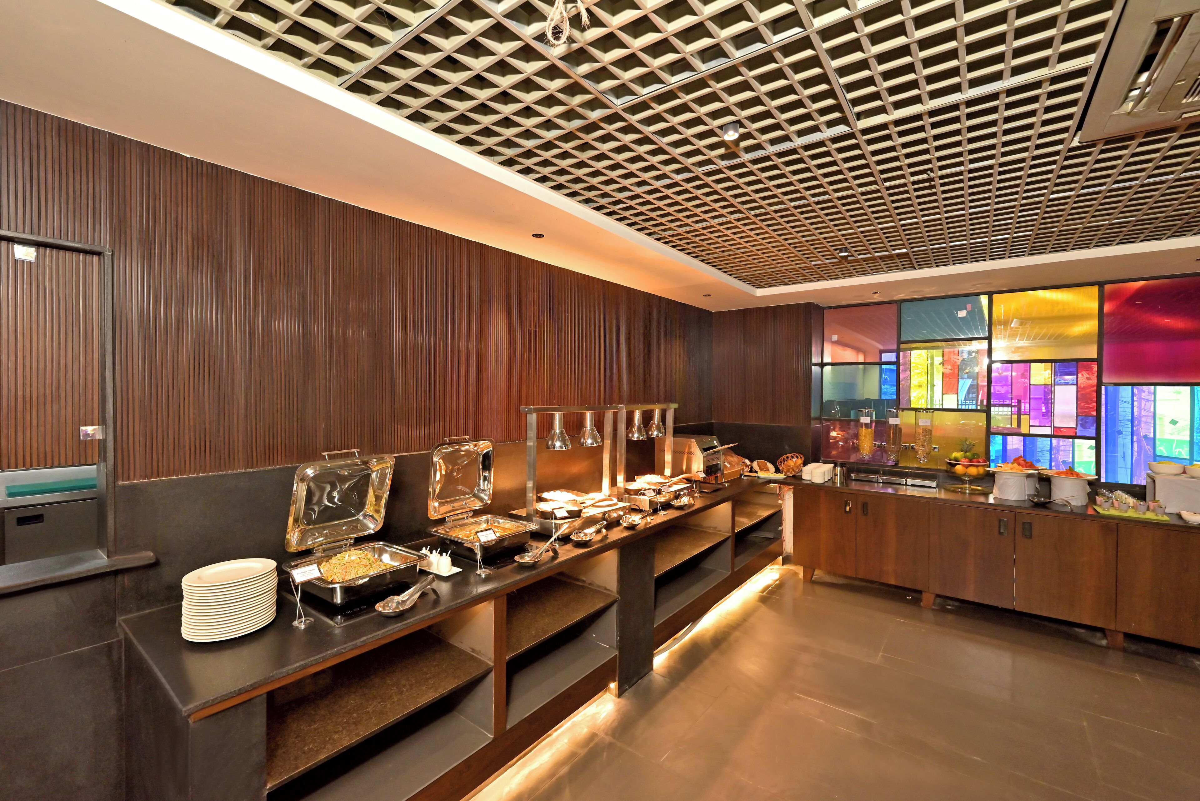 A buffet setup with various food stations and a modern ceiling design.