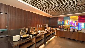 A buffet setup with various food stations and a modern ceiling design.