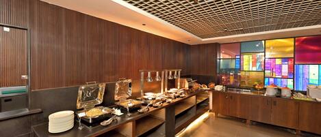 A buffet setup with various food stations and a modern ceiling design.