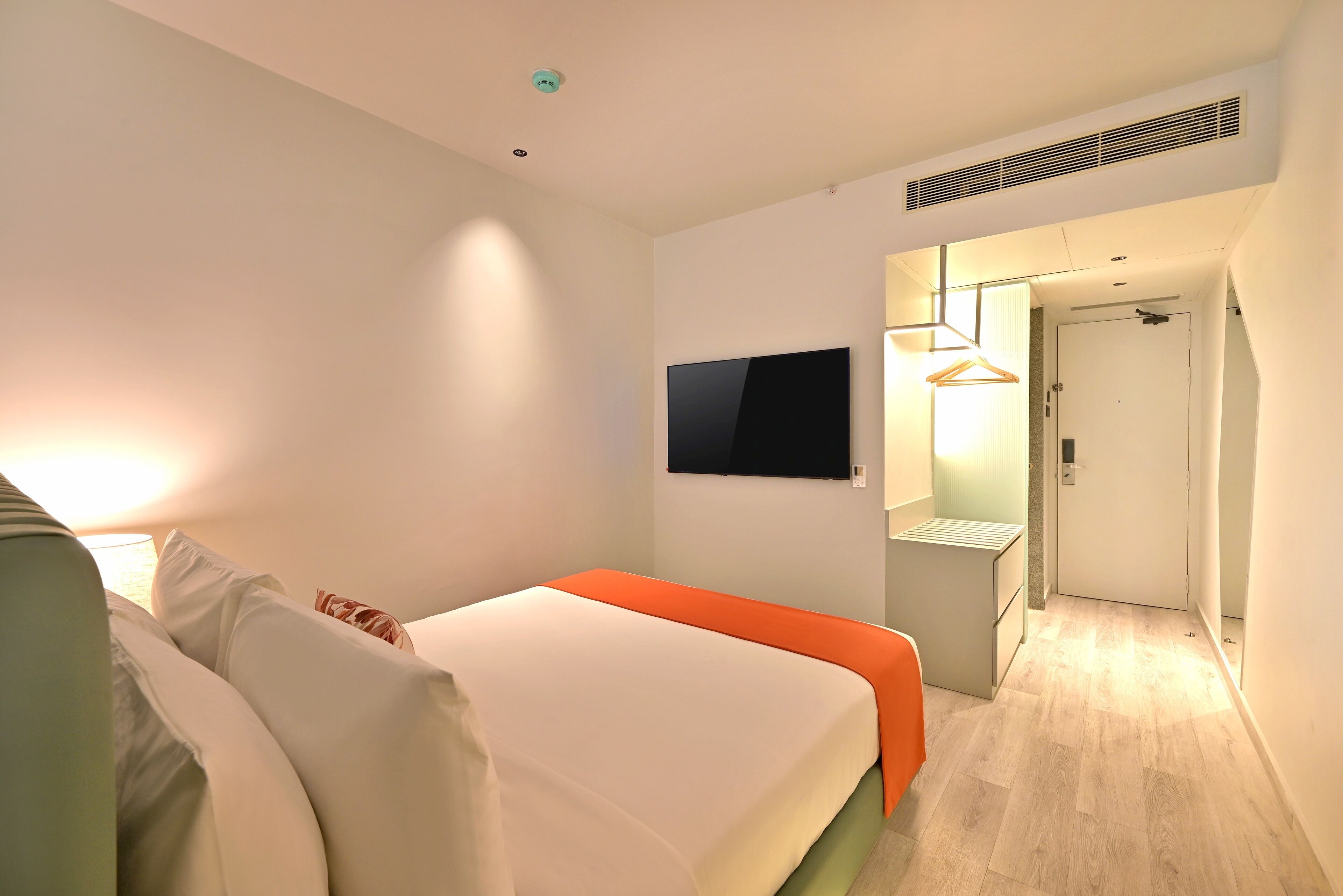 Una moderna camera d'albergo con un letto, una TV a schermo piatto, un comodino e un armadio a muro.