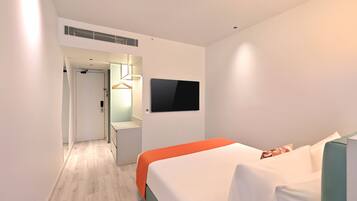 Una habitación de hotel moderna con cama, televisor en la pared y un pasillo que lleva a un baño.