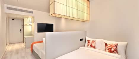 A modern hotel room with a large bed, a flat-screen TV, a ceiling light fixture, and a walk-in closet.