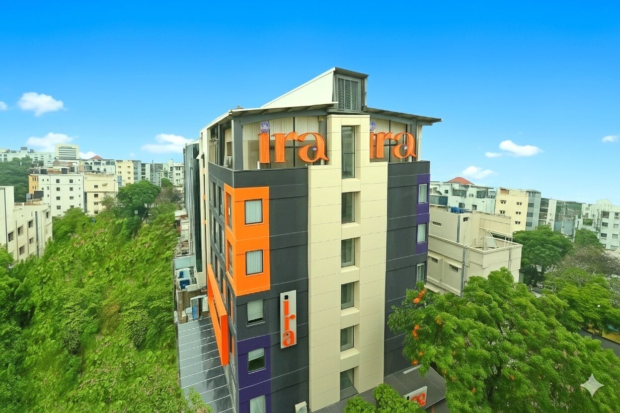 A multi-story building with 'ira' signage, surrounded by greenery and other buildings.