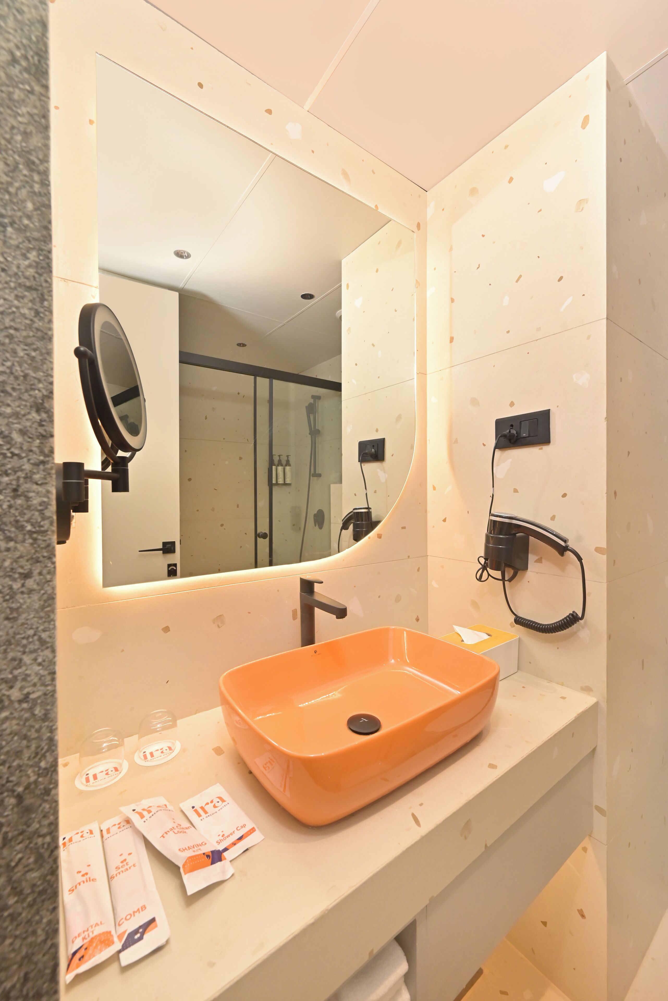A bathroom with a large mirror, an orange sink, and a towel rack.