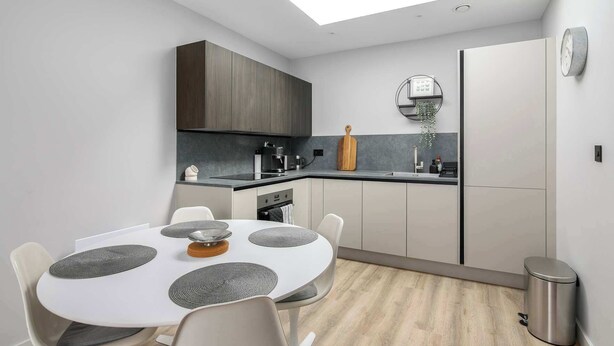 A modern kitchen with a skylight, a dining table with placemats, and a small island.