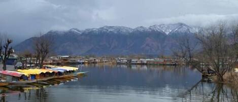 A calm lake with boats and a mountainous backdrop.
