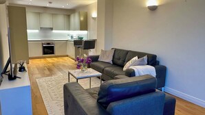 Un salon moderne avec un canapé, une table basse et une petite table d’appoint.