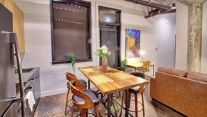A modern kitchen with a wooden table, bar stools, and a brown leather couch. - Chic Ultramodern Loft Suite w/ Designer Features (St. Louis)