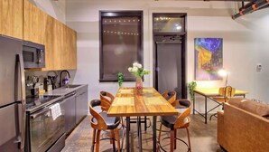 A modern kitchen with a wooden dining table, black chairs, and a coffee machine. - Chic Ultramodern Loft Suite w/ Designer Features (St. Louis)
