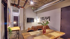 A conference room with a wooden table, chairs, a vase with flowers, and a television on the wall. - Chic Ultramodern Loft Suite w/ Designer Features (St. Louis)