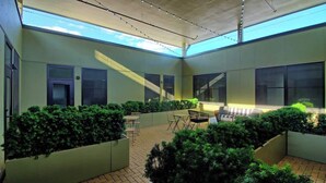 An indoor courtyard with planters, a seating area, and large windows allowing natural light. - Chic Ultramodern Minimalist Loft Suite + Patio (Saint Louis)