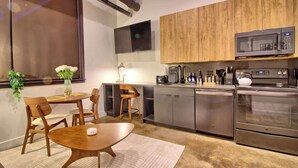 A modern kitchen with wooden cabinets, stainless steel appliances, and a dining area with a wooden table and chairs. - Chic Ultramodern Minimalist Loft Suite + Patio (Saint Louis)