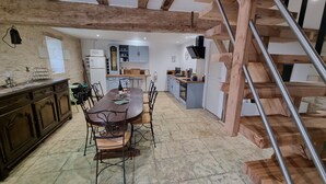 A spacious dining area with a wooden table and chairs, a kitchen in the background, and a wooden staircase. - Le Figuier:8-person gite, heated pool and leisure facilities 25 minutes from Futuroscope. (Mazeuil)