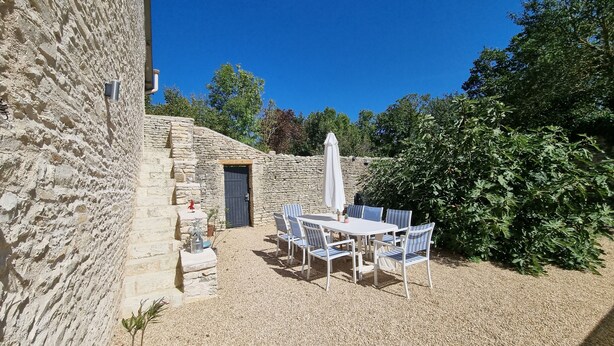 A stone building with a gravel patio, outdoor seating, and a door. - Le Figuier:8-person gite, heated pool and leisure facilities 25 minutes from Futuroscope. (Mazeuil)