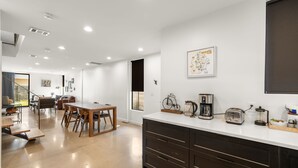 A modern kitchen with a white countertop, dark cabinets, and a coffee maker. - Austin Luxury 5BR Modern House | ACL x Formula 1 (Austin)
