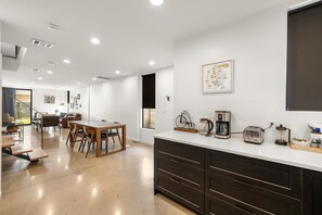 A modern kitchen with a white countertop, dark cabinets, and a coffee maker. - Austin Luxury 5BR Modern House | by Barclé (Austin)