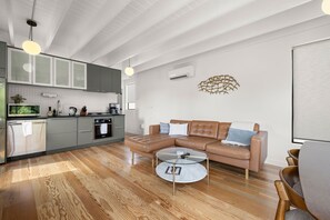 A modern kitchen with grey cabinets, a round dining table, and a leather sofa.