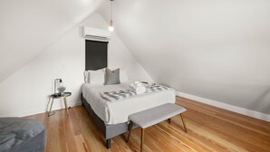 A modern bedroom with a bed, bedside table, bench, and an air conditioning unit. - Austin Luxury 5BR Modern House | ACL x Formula 1 (Austin)