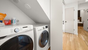 A laundry area with two washing machines, a ceiling vent, and a white door leading to another room. - Austin Luxury 5BR Modern House | ACL x Formula 1 (Austin)