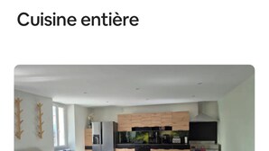 A modern kitchen with wooden cabinets, a central island, and a dining area with wooden chairs. - Gîte de La Berthuinière (Saint-Martin-en-Vercors)