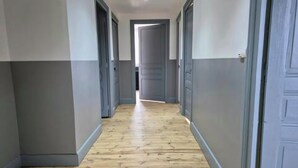 A hallway with wooden flooring and grey walls, leading to multiple doors. - Gîte de La Berthuinière (Saint-Martin-en-Vercors)