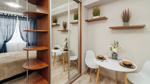 Una habitación moderna con una mesa de comedor, sillas blancas y estanterías de madera con plantas.