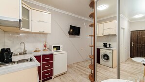 Una cocina compacta equipada con microondas, pileta y un refrigerador pequeño.