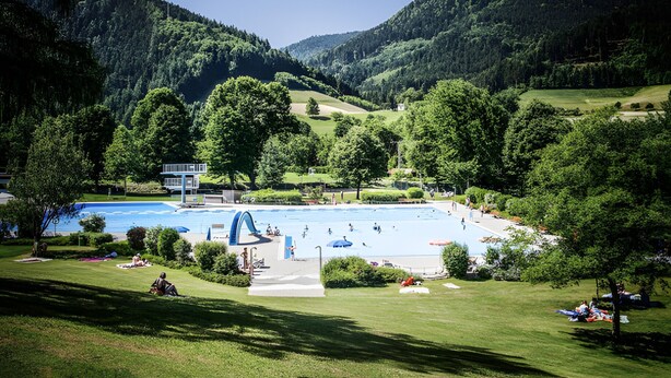 Una piscina rodeada de exuberante vegetación y colinas.
