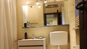 A bathroom with a toilet, sink, mirror, and shower curtain.
