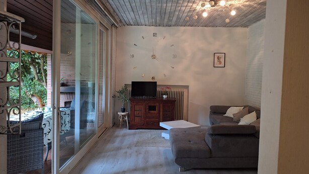 A living room with a fireplace, a television, a sofa, and a glass door leading to an outdoor area.