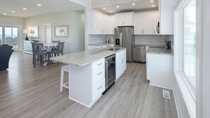 A modern kitchen with white cabinetry, a granite countertop, and stainless steel appliances. - 7 Bedroom, Ocean Front Paradise - 1 To Sea (Garden City)