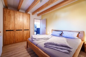 Une chambre à coucher avec un lit en bois, une armoire et une porte donnant sur une autre pièce.