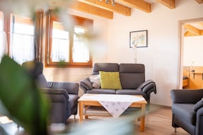 Un salon avec un canapé, des fauteuils, une table basse et un tableau au mur.