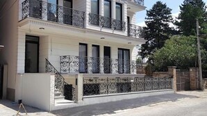 Un edificio a due piani con balconi, un ingresso chiuso da cancello e un vialetto lastricato.