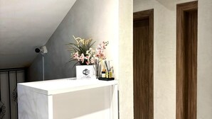 Un bagno moderno con un piano lavabo in marmo bianco, una telecamera di sicurezza a muro e un elegante vaso con orchidee.