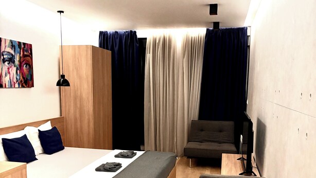 Una camera da letto moderna con un letto, una scrivania, una sedia e una televisione.