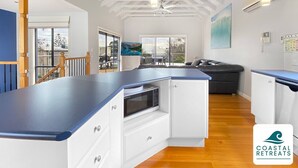 Una cocina moderna con encimera azul, armarios blancos y un microondas integrado.