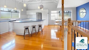 Una cocina amplia con una isla grande, taburetes de madera e iluminación colgante.