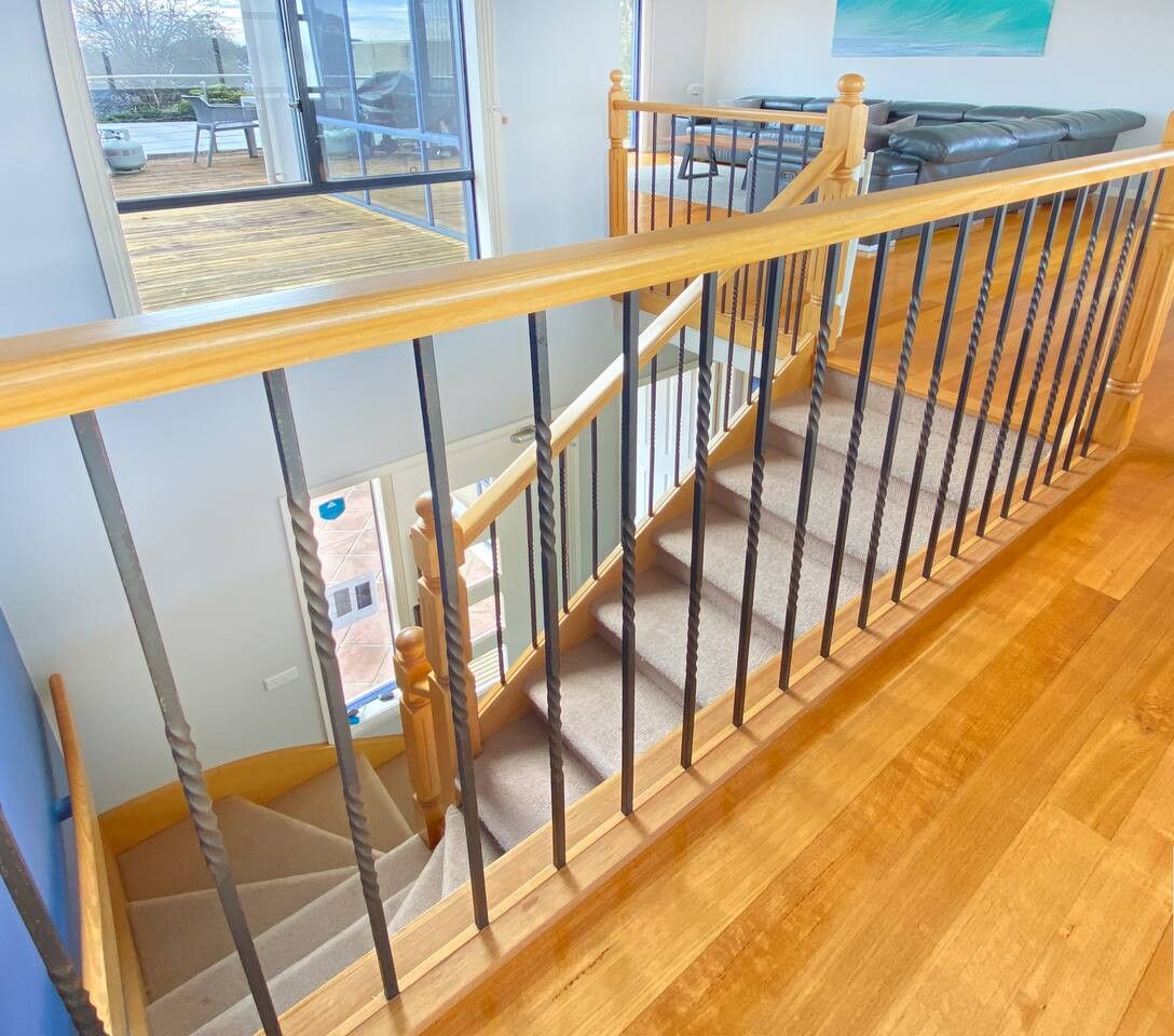 Een houten trap met glazen leuning die naar een tweede verdieping leidt.