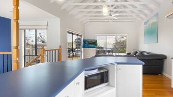 A modern kitchen with a blue countertop, white cabinetry, and a built-in microwave.