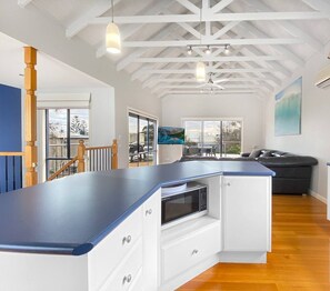 Une cuisine moderne avec un plan de travail bleu, des meubles blancs et un four à micro-ondes encastré.