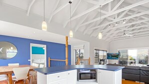 Une cuisine moderne avec des meubles blancs, un plan de travail bleu et un four à micro-ondes encastré.