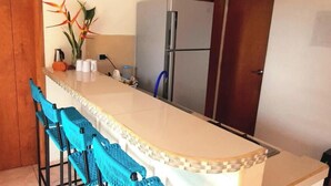 A kitchen with a central island, blue chairs, and a refrigerator.